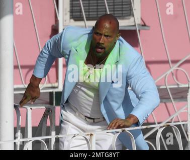 EXCLUSIF !! Portant une veste bleue pour bébé, une chemise blanche, un pantalon blanc, des chaussures blanches, un collier crucifix et ce qui semble être de la goo verte sur son visage et sa poitrine, Dwayne « The Rock » Johnson et son double stunt sont vus sur le terrain pour filmer une séquence d'action pour son prochain film « pain & gain ». Le film est réalisé par Michael Bay, réalisateur de 'Transformerss', et devrait sortir en 2013. Maimi, Floride. 14th avril 2012. Banque D'Images