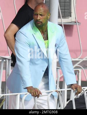 EXCLUSIF !! Portant une veste bleue pour bébé, une chemise blanche, un pantalon blanc, des chaussures blanches, un collier crucifix et ce qui semble être de la goo verte sur son visage et sa poitrine, Dwayne « The Rock » Johnson et son double stunt sont vus sur le terrain pour filmer une séquence d'action pour son prochain film « pain & gain ». Le film est réalisé par Michael Bay, réalisateur de 'Transformerss', et devrait sortir en 2013. Maimi, Floride. 14th avril 2012. Banque D'Images