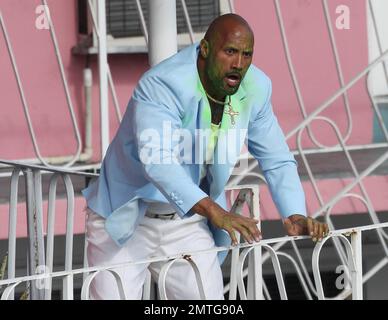 EXCLUSIF !! Portant une veste bleue pour bébé, une chemise blanche, un pantalon blanc, des chaussures blanches, un collier crucifix et ce qui semble être de la goo verte sur son visage et sa poitrine, Dwayne « The Rock » Johnson et son double stunt sont vus sur le terrain pour filmer une séquence d'action pour son prochain film « pain & gain ». Le film est réalisé par Michael Bay, réalisateur de 'Transformerss', et devrait sortir en 2013. Maimi, Floride. 14th avril 2012. Banque D'Images