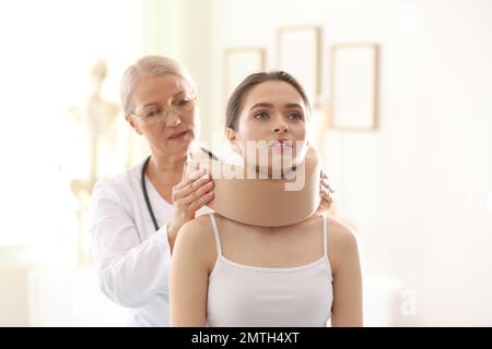 Orthopédiste féminin appliquant le col cervical sur le cou du patient en clinique Banque D'Images