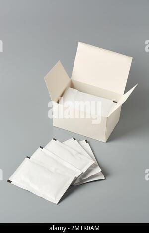 sachets blancs vierges et avec une boîte vierge isolée sur fond gris neutre, modèle de maquette d'emballage alimentaire ou pharmaceutique Banque D'Images