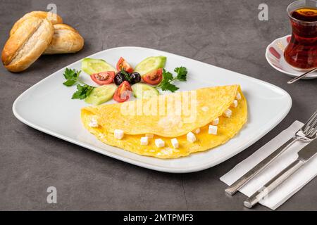 Omelette au fromage feta aux olives et aux tomates sur une assiette en porcelaine blanche Banque D'Images