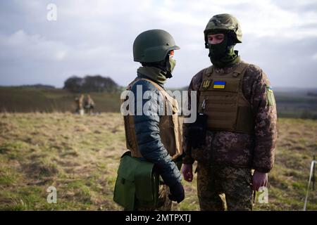 Les soldats ukrainiens se parlent mutuellement en tant que Secrétaire aux Affaires étrangères James intelligemment, Secrétaire à la Défense Ben Wallace, Ministre australien des Affaires étrangères, le sénateur Penny Wong et Vice-Premier ministre Richard Marles, en visite dans la plaine de Salisbury dans le Wiltshire, où les Forces armées australiennes soutiennent la formation de recrues ukrainiennes dirigée par le Royaume-Uni. Date de la photo: Mercredi 1 février 2023. Banque D'Images