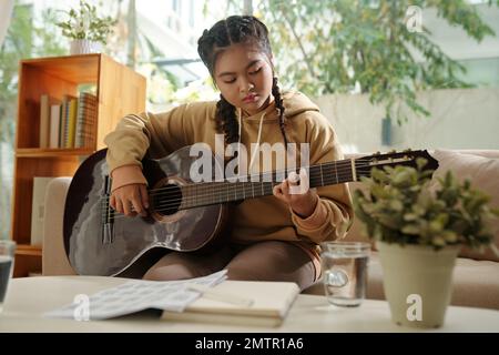 Talentueuse et créative teenge fille jouant de la guitare à la maison travaillant sur une nouvelle chanson Banque D'Images