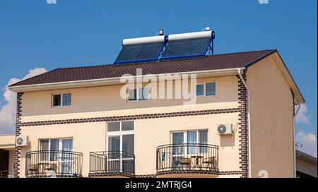 Chauffe-eau solaire sur le toit, beau fond de ciel bleu. Banque D'Images