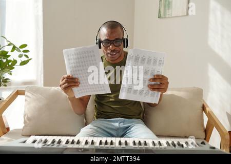 Joyeux professeur de musique montrant des papiers avec des exercices de notes de musique Banque D'Images