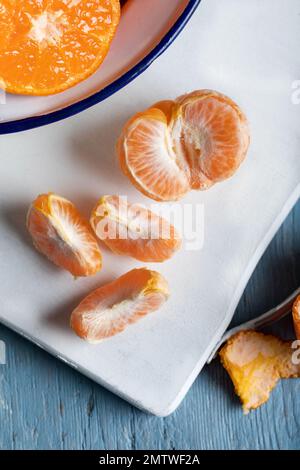 Tranches de mandarine mûre jaune sur une table en bois. Agrumes, mandarines ou oranges. Vue de dessus. Banque D'Images