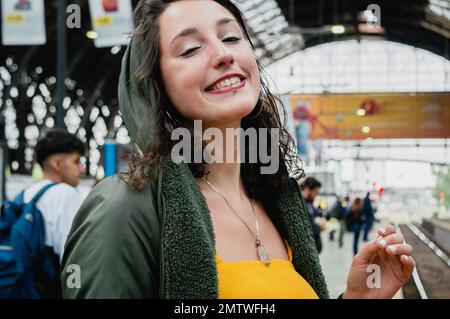 Portrait d'une jeune femme Latina à la peau blanche, vêtue de jaune, regardant l'appareil photo, elle est très heureuse parce qu'elle va en train à Banque D'Images