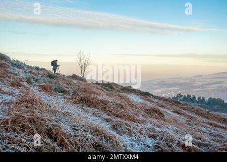 Photographe utilisant un trépied et prenant des photos de paysage au lever du soleil sur Ilkley Moor par une journée très froide avec le gel couvrant le sol dans West Yorkshire, en Banque D'Images