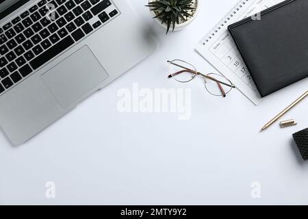 Composition avec ordinateur portable, lunettes et articles de papeterie sur fond blanc, vue du dessus Banque D'Images