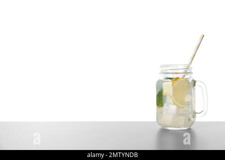 Délicieuse limonade dans un pot de maçon sur une table grise sur fond blanc. Espace pour le texte Banque D'Images