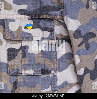 Badge en métal avec le drapeau de l'Ukraine en forme de coeur sur la veste militaire. Soutien à l'Ukraine. La guerre en Ukraine. Thème drapeau de l'Ukraine Banque D'Images