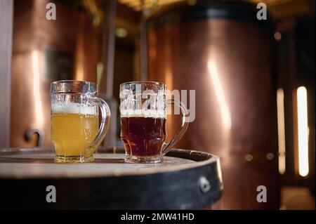 Bière artisanale légère et foncée fraîchement préparée dans une tasse en verre sur le fût Banque D'Images