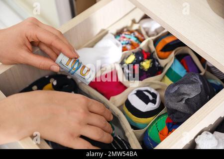 Femme cachant de l'argent dans le tiroir avec des chaussettes, gros plan. Économies financières Banque D'Images