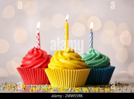 De délicieux petits gâteaux d'anniversaire avec des bougies allumées sur la table Banque D'Images