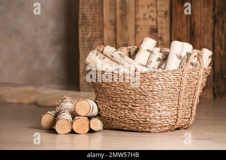 Panier en osier avec bois coupé sur le sol à l'intérieur Banque D'Images