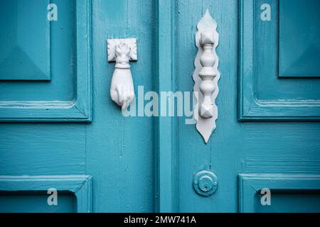 Un porte-outil en forme de main et une poignée en métal sur une ancienne porte peinte en bleu. Banque D'Images