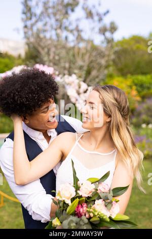 Vertical de la mariée et du marié heureux et variés avec bouquet embrassant à l'extérieur de mariage Banque D'Images