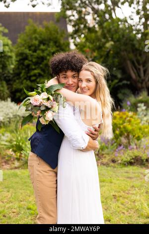 Portrait vertical de la mariée et du marié heureux et variés embrassant au mariage dans le jardin Banque D'Images