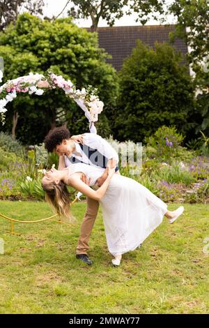 Vertical de heureux divers mariés embrassant, dansant au mariage dans le jardin, espace de copie Banque D'Images