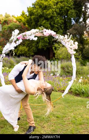 Vertical de la mariée et marié heureux et divers embrassant, dansant au mariage dans le jardin, avec espace de copie Banque D'Images