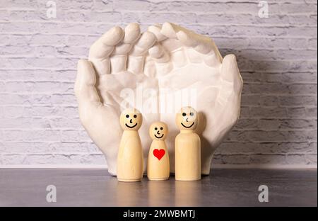 Figurines en bois d'une jeune famille sur un fond blanc. Concept d'un jeune couple marié forte et saine. Un couple aimant s'attend à ce que la naissance d'un Banque D'Images