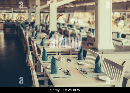 Un accent sélectif sur une table de salle à manger, le placement de l'assiette, l'assiette, les serviettes bleues, et l'argenterie d'un restaurant sur un porche d'un complexe Banque D'Images
