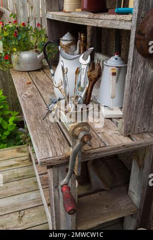 Ancien établi décoré de bouilloires à thé anciennes et d'un broyeur à viande manuel rempli de vieilles clés sur une terrasse en bois derrière la vieille maison, Québec, Canada Banque D'Images