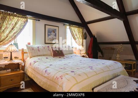 Très grand lit dans la chambre principale à l'étage à l'intérieur de l'ancienne maison de style cottage Canadiana reconstruite en 1886. Banque D'Images