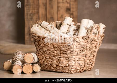 Panier en osier avec bois coupé sur le sol à l'intérieur Banque D'Images