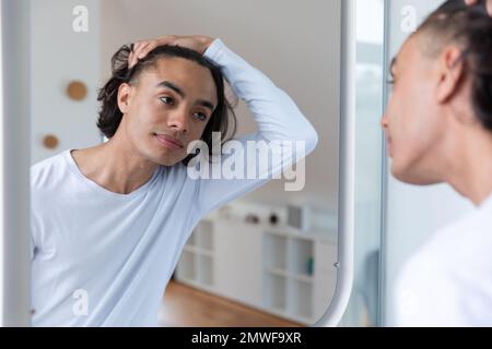 Joyeux biracial homme regardant dans le miroir dans la salle de bains Banque D'Images