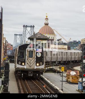 Le métro rejoint la station de métro Marcy Street dans le quartier de Williamsburg, le premier arrêt de Brooklyn depuis Manhattan. Le pont de Williamsburg et l'ancien dôme de Williamsburg Bank en arrière-plan. Banque D'Images