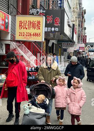 Des milliers de personnes chinoises et autrement se rassemblent dans Chinatown à Manhattan pour célébrer et apporter l'année du lapin le premier jour du nouvel an lunaire 2023. Mère avec enfants marche le long de East Broadway. Banque D'Images