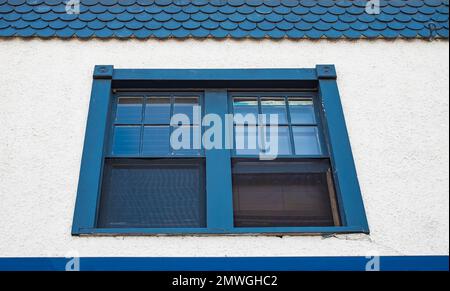 Ancienne fenêtre en bois sur le mur blanc de la vieille maison traditionnelle. Une ancienne maison rustique avec fenêtre. Façade d'une maison avec fenêtre en bois. Personne, photo de rue Banque D'Images