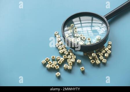 Concept d'apprentissage et d'éducation. Recherche de mots-clés. Apprentissage des langues. Loupe sur un bouquet de perles de l'alphabet. Banque D'Images