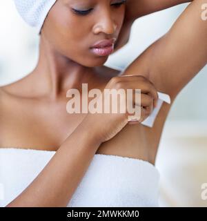 Toilettage personnel. une jeune femme attirante la cirant sous les bras. Banque D'Images