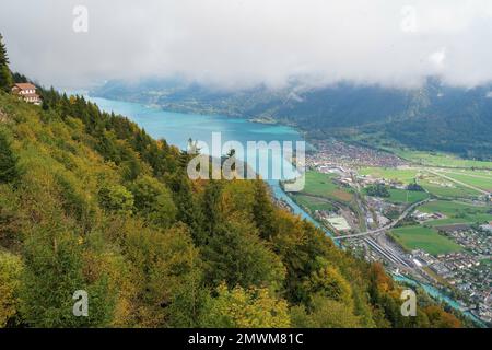Vue d'automne depuis la forêt au-dessus d'Interlaken, Suisse avec un bâtiment perché sur la montagne Banque D'Images