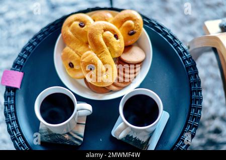 Une vue de dessus de savoureux petits pains avec raisins secs sur la table avec les tasses de café noir Banque D'Images