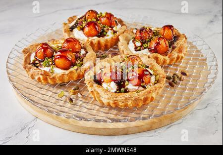 Tartelettes au melon, mascarpone et pistaches sur une plaque transparente. Banque D'Images