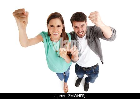 Montrant leur frustration à l'égard du système. Prise de vue en grand angle d'un jeune couple dans un studio en secouant ses poings avec colère contre la caméra. Banque D'Images