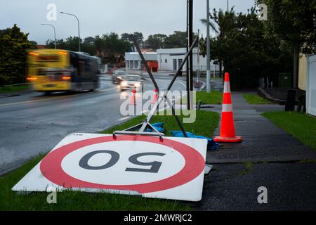 50km symbole de limite de vitesse soufflé par le vent. Les voitures hors-focus se déplaçant sur la route. Auckland après la tempête. Banque D'Images