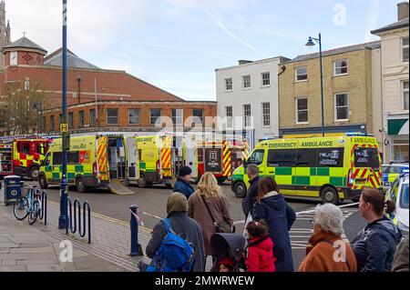 Les gens regardent tandis que les ambulances et les moteurs d'incendie assistent à une scène après qu'une voiture s'est écrasée par une fenêtre de magasin de charité dans le quartier commerçant Banque D'Images