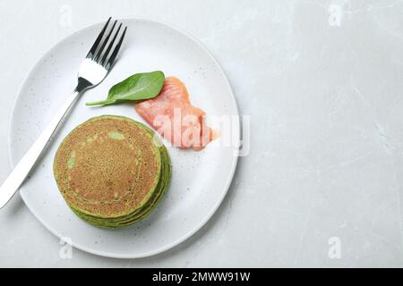 Savoureuses crêpes aux épinards servies sur une table en marbre gris clair, vue sur le dessus. Espace pour le texte Banque D'Images