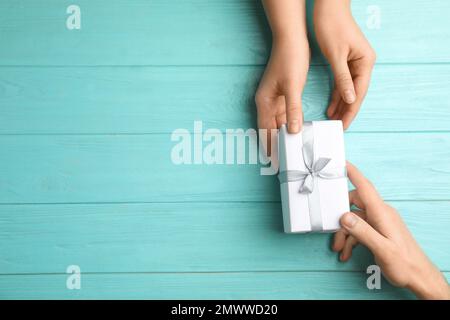 Fille donnant cadeau à son père à table en bois bleu clair, vue de dessus avec espace pour le texte. Bonne journée des pères Banque D'Images