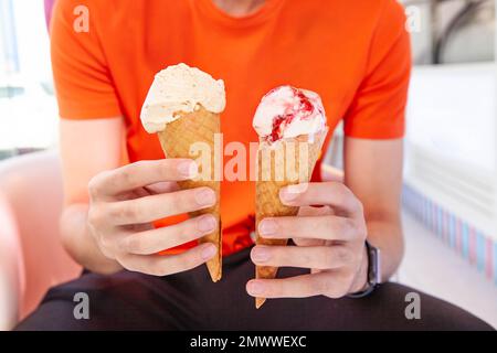 Main tenant la glace à glace à cône en deux mains Banque D'Images