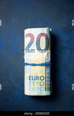 Vingt billets en euros ont roulé avec un élastique sur une table. Banque D'Images