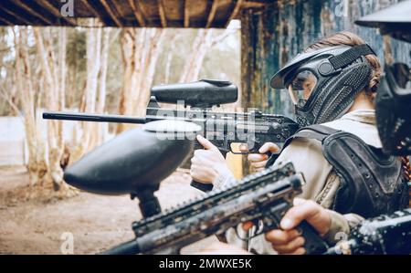 Paintball, arme à feu et cible avec les gens, l'action et les sports en plein air, champ de bataille et soldat, concentration pendant le jeu de guerre. Sport extrême, arme d'équipe et Banque D'Images