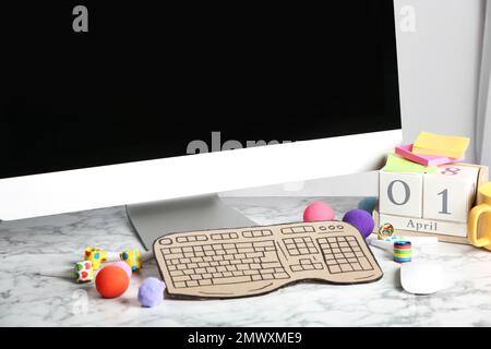 Ordinateur avec clavier en carton sur table en marbre blanc. Le jour de la fête du poisson d'avril Banque D'Images