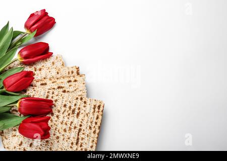 Savoureux matzos et fleurs sur fond blanc, plat avec espace pour le texte. Seder de Pâque (Pesach) Banque D'Images