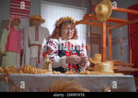 femme tisse divers jouets et vêtements de paille. l’artisanat populaire Banque D'Images